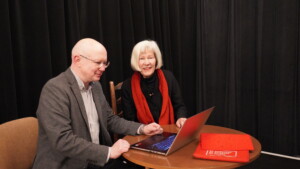 Dwóch prelegentów, mężczyzna i kobieta, siedzi przy stoliku z laptopem.